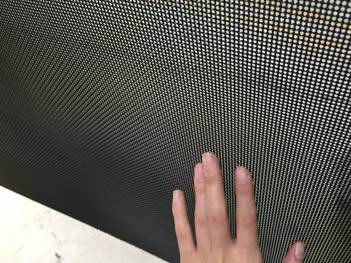 A piece of square opening stainless steel mesh with black polyethylene coating and a hand on it
