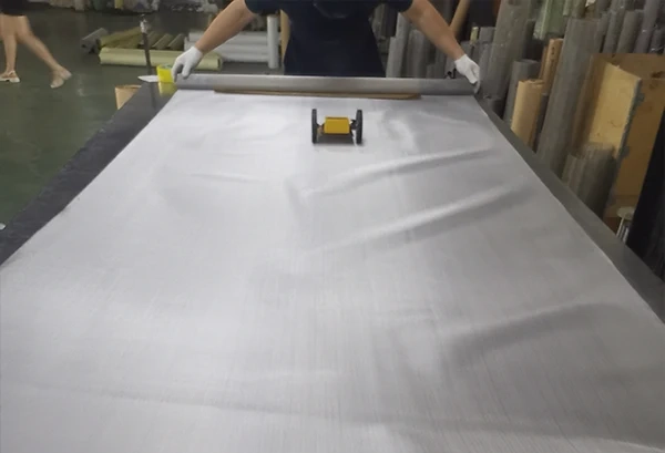 A worker is measuring the length of 316/316l stainless steel mesh with a cart