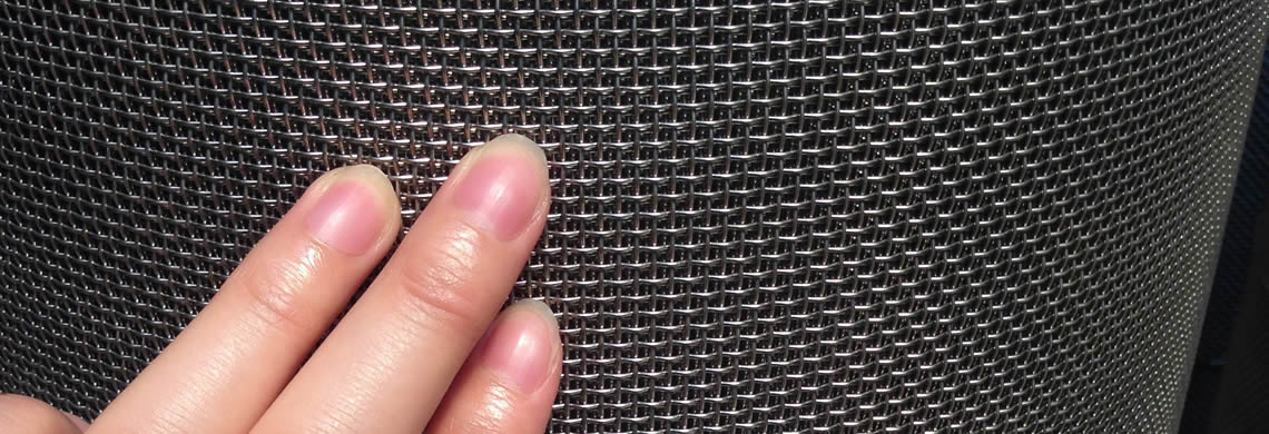 A roll of stainless steel mesh screen and a women's hand on it